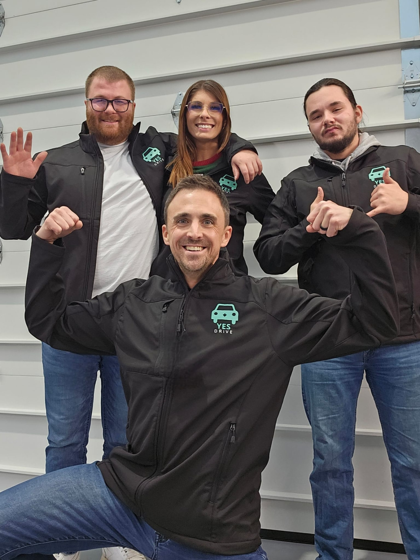 Four Yes Drive team members in branded jackets, joking around
