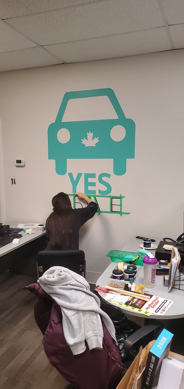 A team member hand-painting the Yes Drive logo on the office wall