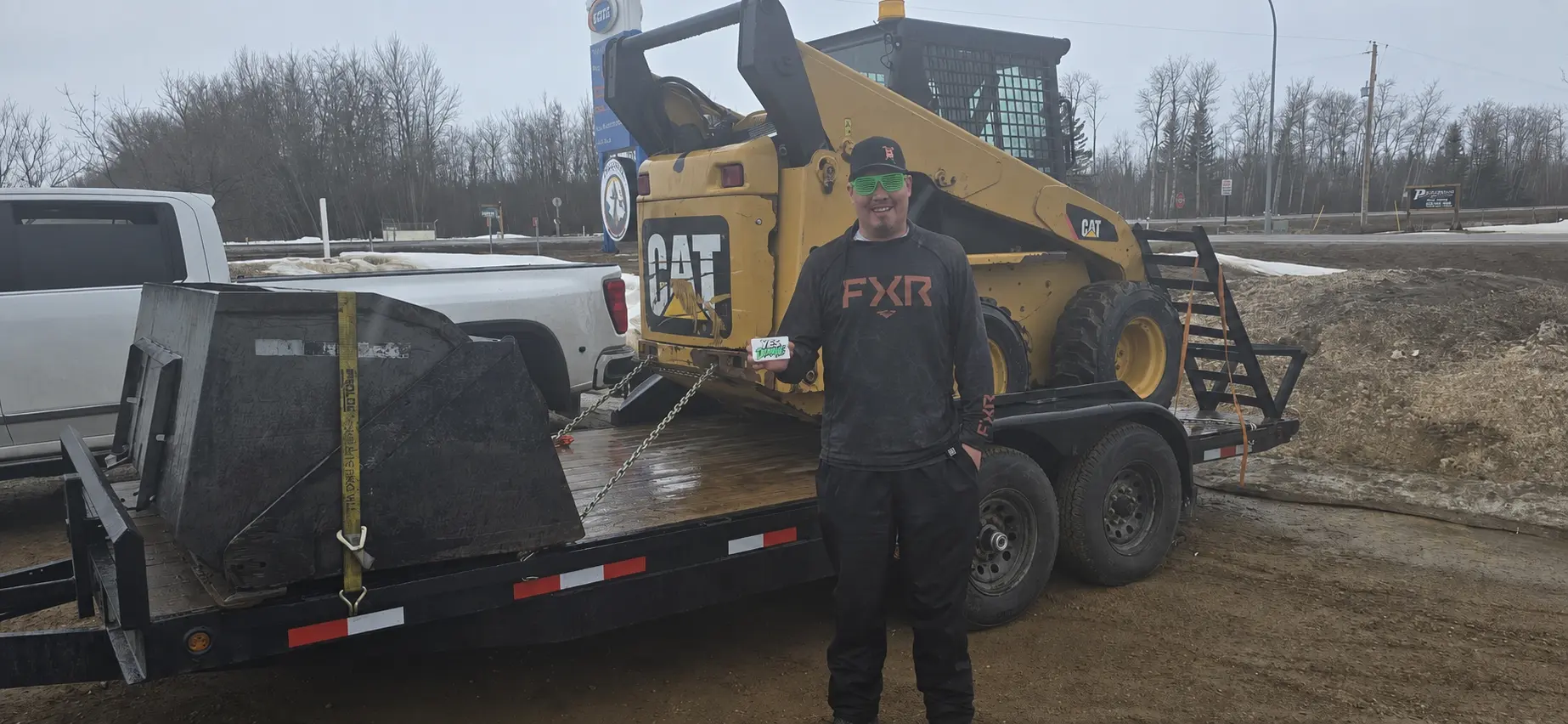 A customer with a yellow skid steer loaded on a flatbed trailer