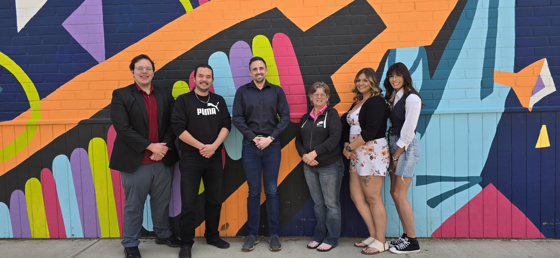 The Yes Drive team standing together in front of a painted mural