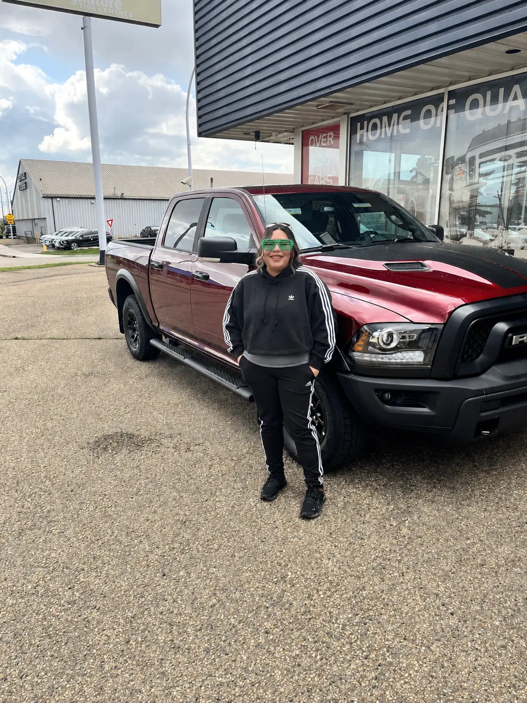A customer beside her dark red Ram pickup at the dealership