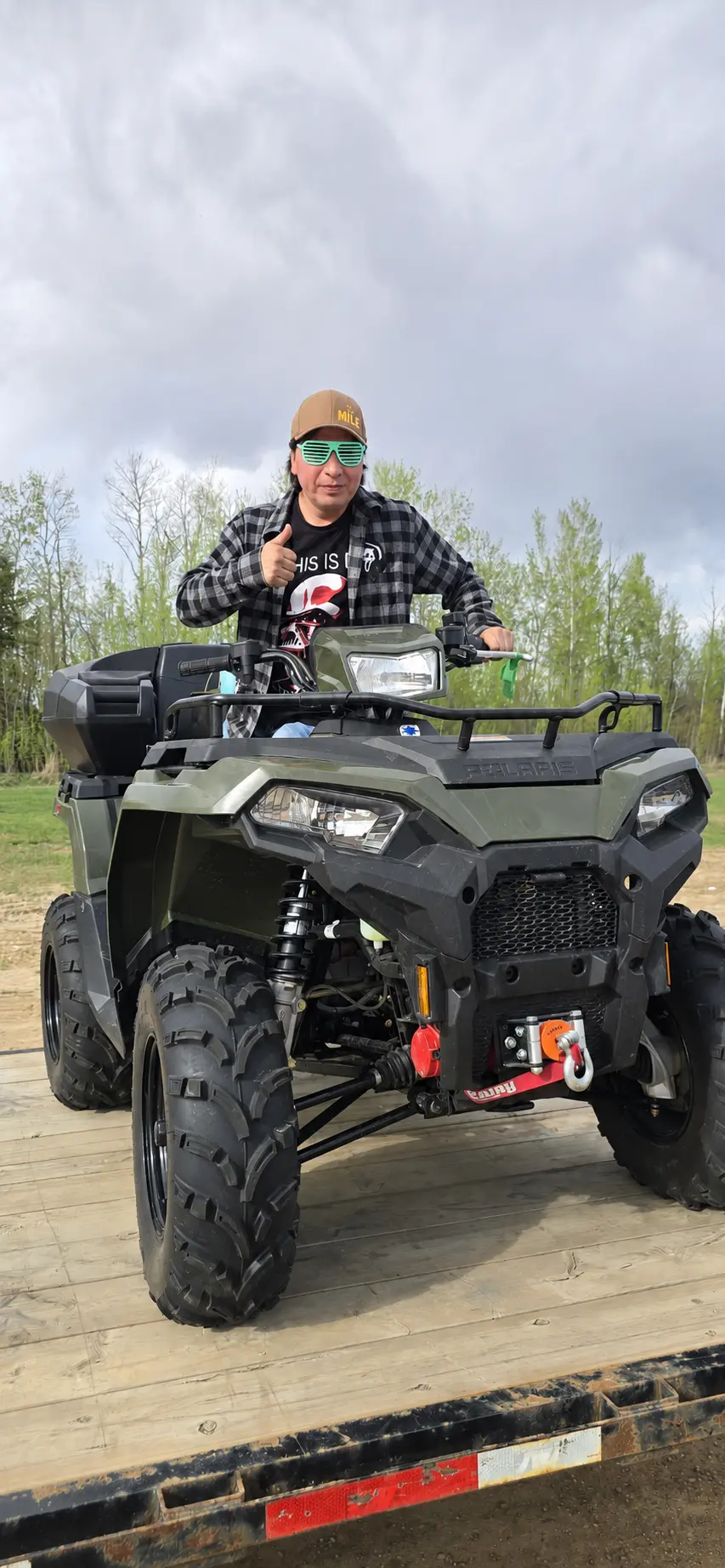 A customer on a green Polaris ATV loaded on a deck trailer