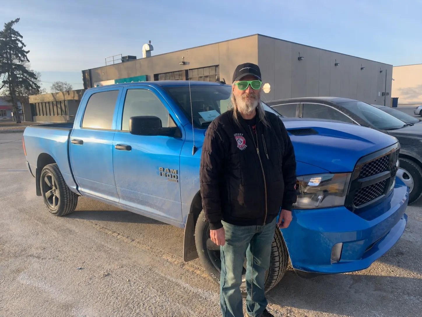 A customer in front of his blue Ram 1500 pickup