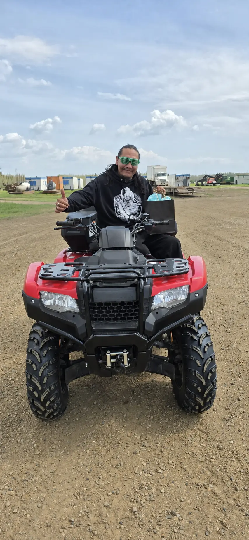 A customer on his new red ATV giving a thumbs up
