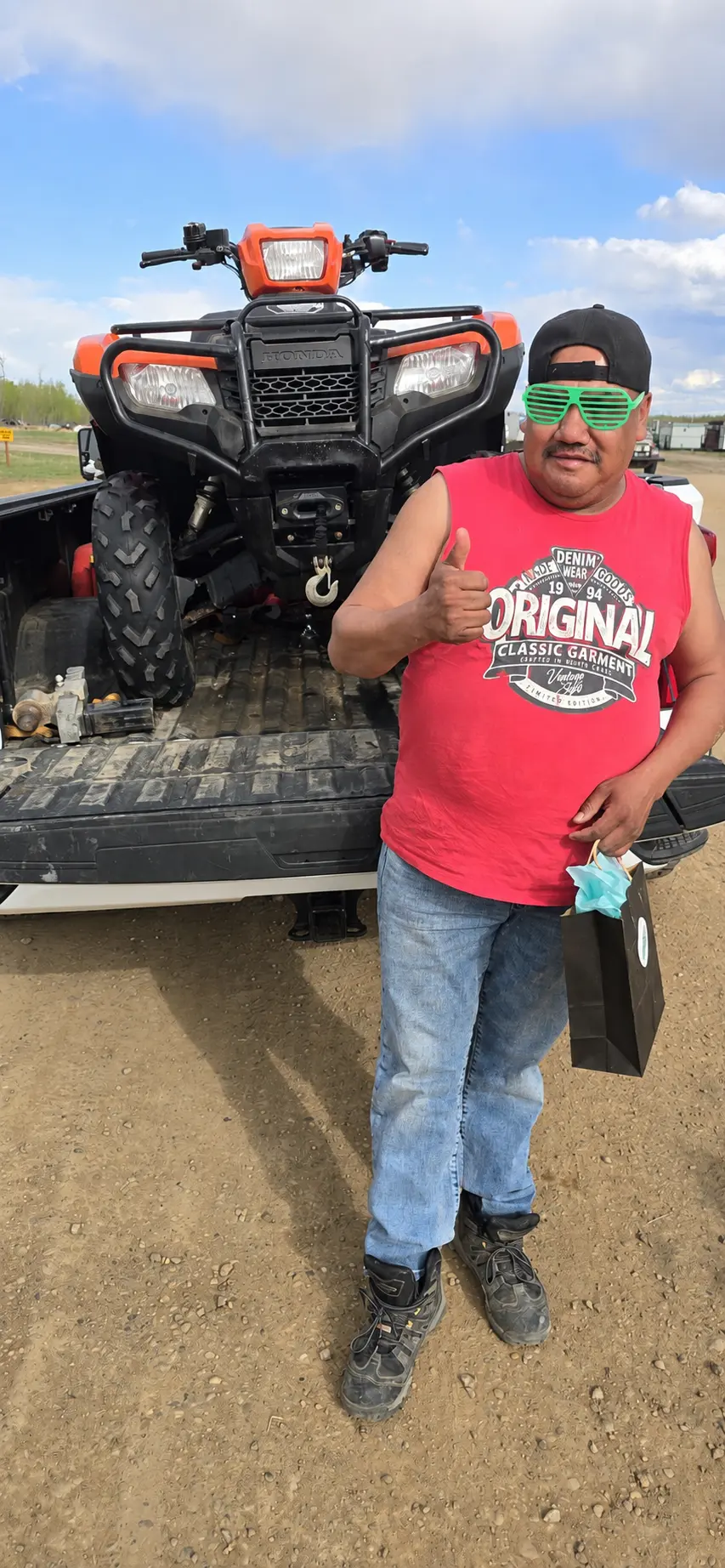A customer giving a thumbs up beside an orange ATV in a truck box