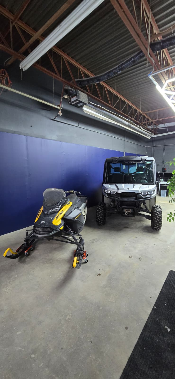 A snowmobile and an enclosed side-by-side staged inside the shop