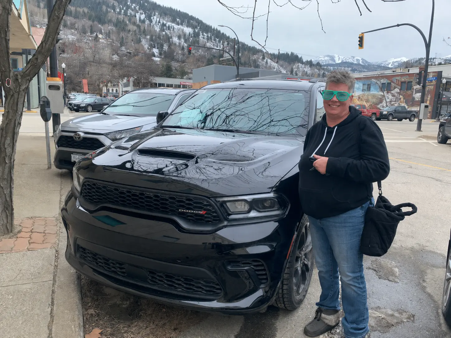 A customer beside her black Dodge Durango after delivery